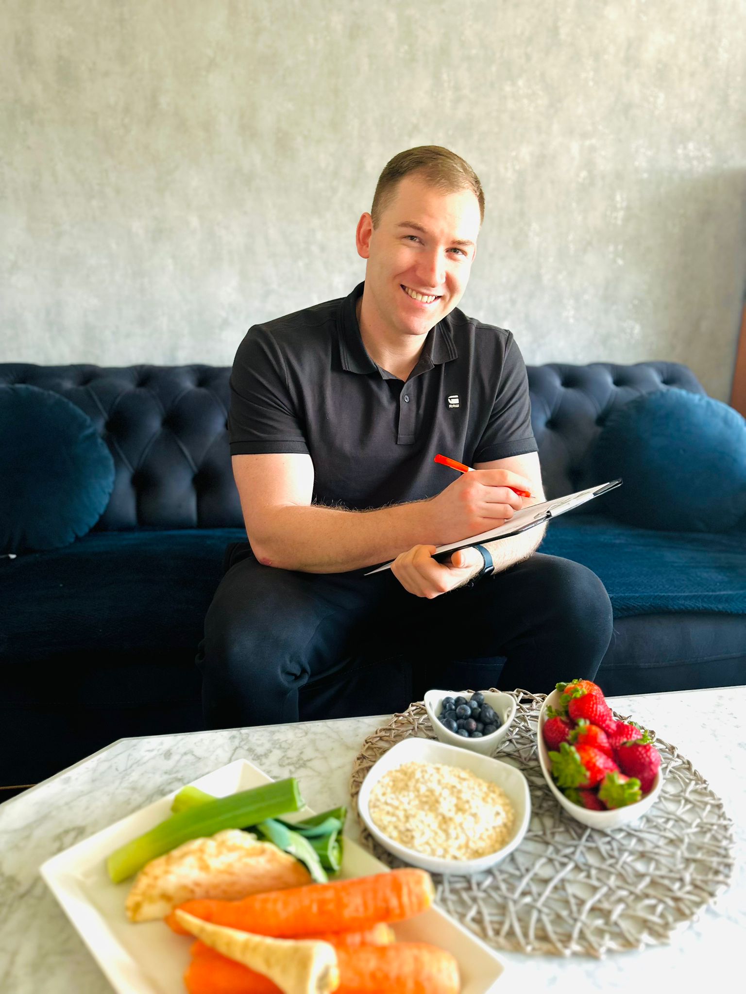 Justin auf einer Couch mit frischen Lebensmitteln für die Ernährungsberatung.