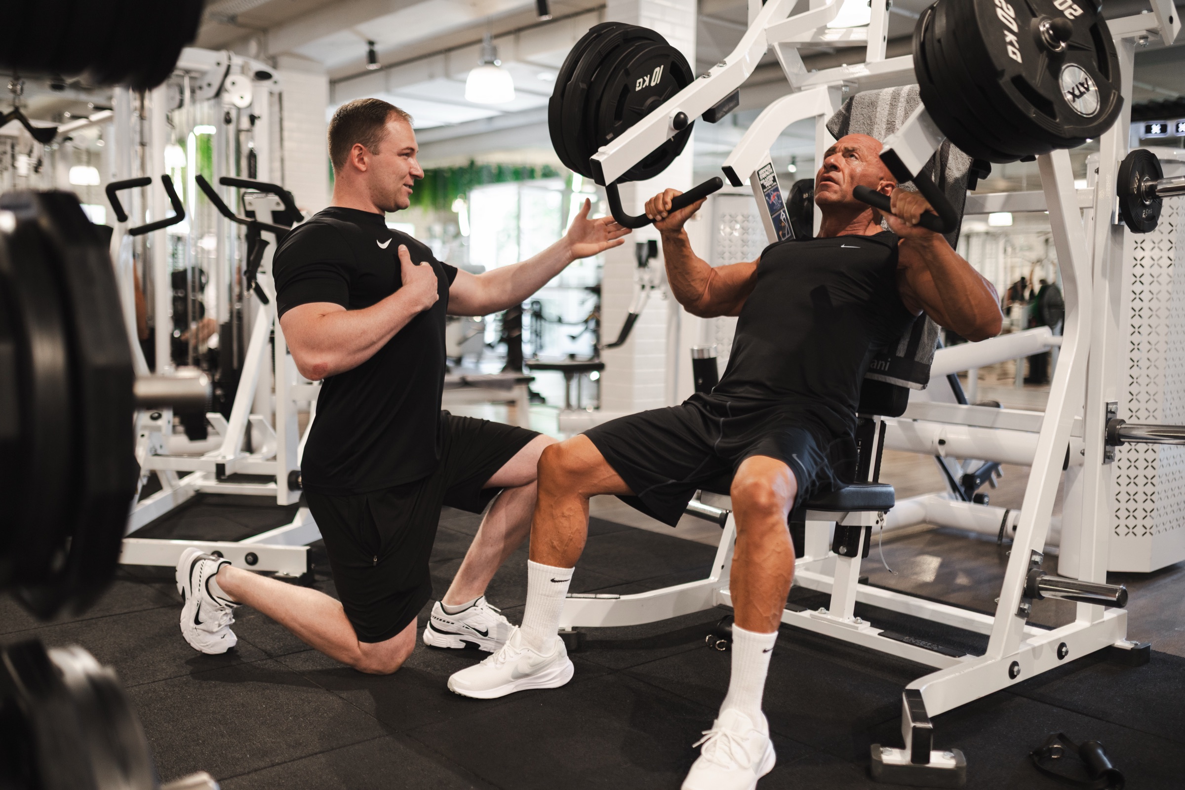 Justin begleitet einen Kunden beim Training an der Brustpresse.